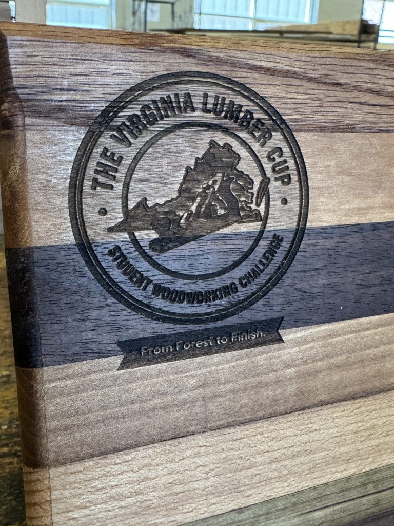 Close-up of the engraved Virginia Lumber Cup logo on a laminated wood display board.