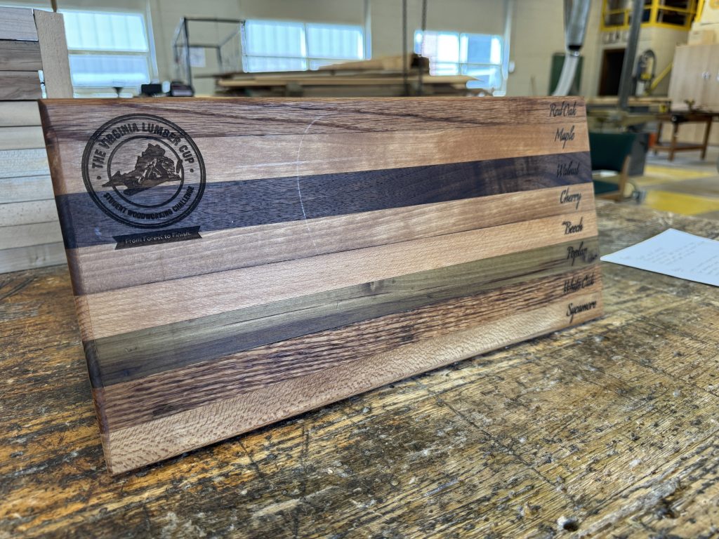 Polished laminated wood display board with multiple wood species stripes, engraved labels, and the Virginia Lumber Cup logo.
