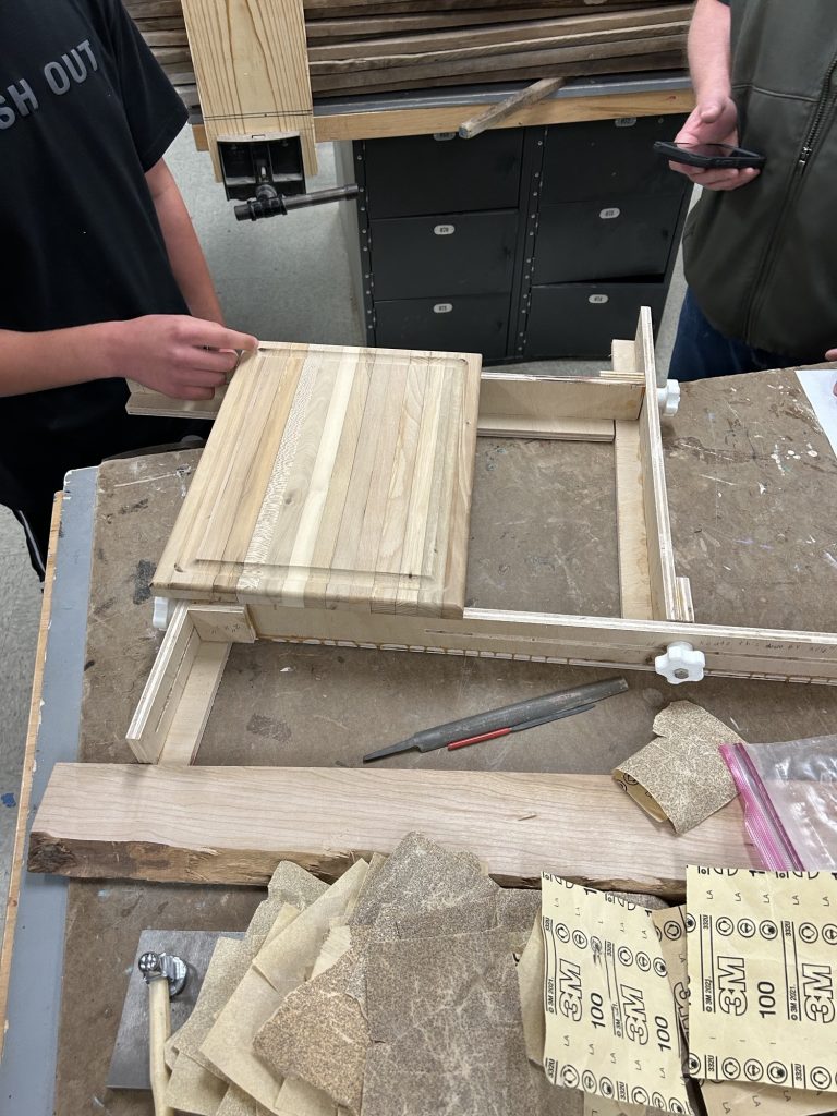Rectangular spacer-stick cutting board in a routing jig with a raised center section and shaped edges.