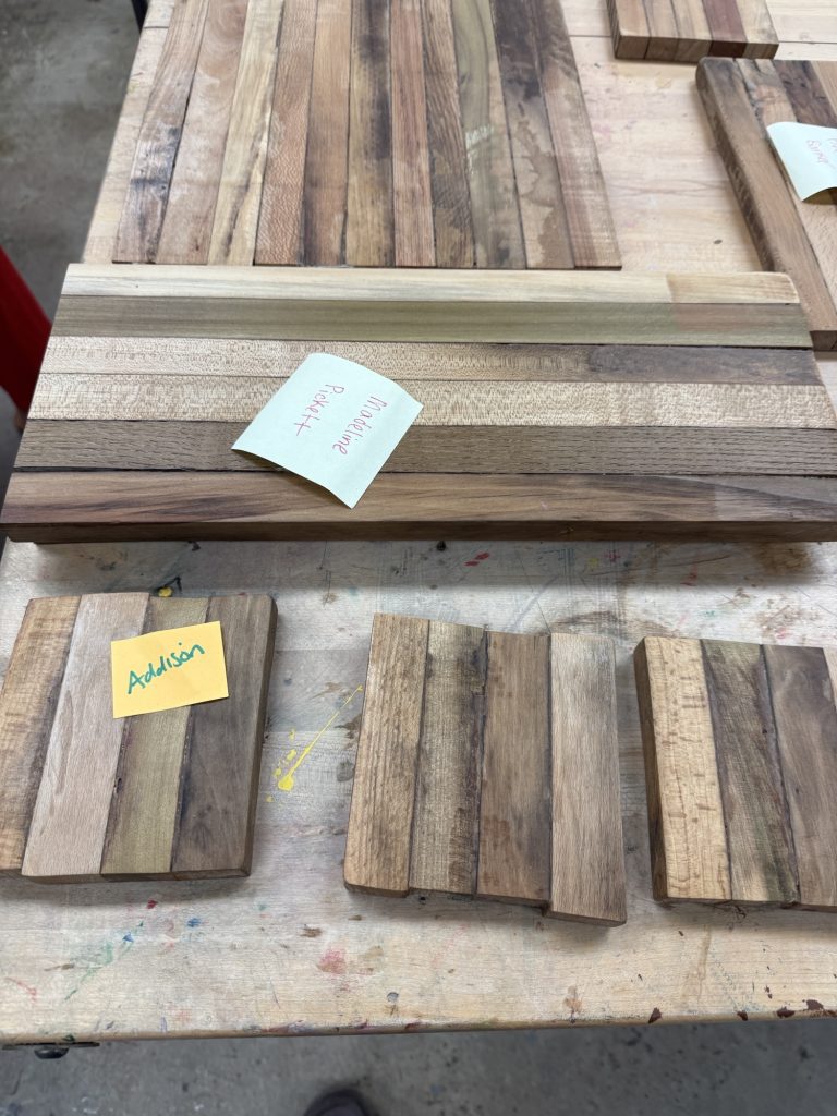 Close-up of long and small laminated cutting boards or serving boards made from mixed spacer-stick strips.