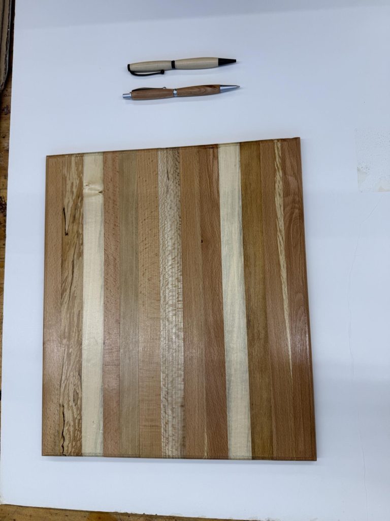 Polished striped cutting or serving board displayed with two handcrafted wooden pens.