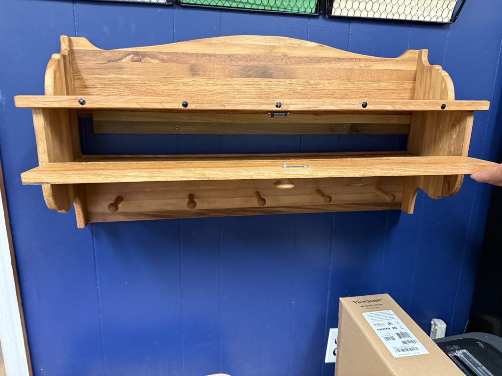 Wall-mounted shelf and coat rack with two shelves, peg hooks, and curved side supports in a natural wood finish.