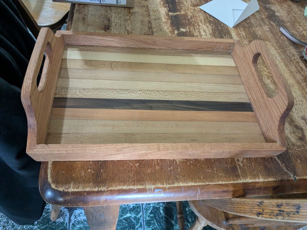 Handled rectangular serving tray with a laminated striped wood base and shaped side handles.